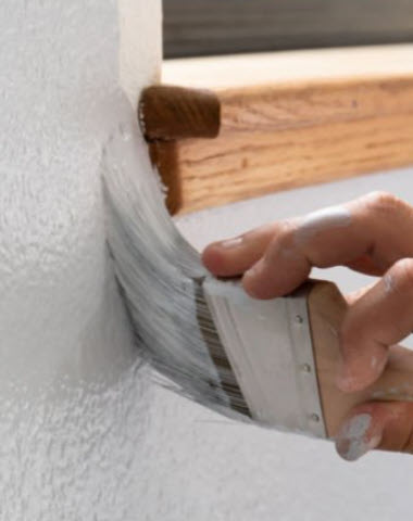 Decorator painting a wall around a window